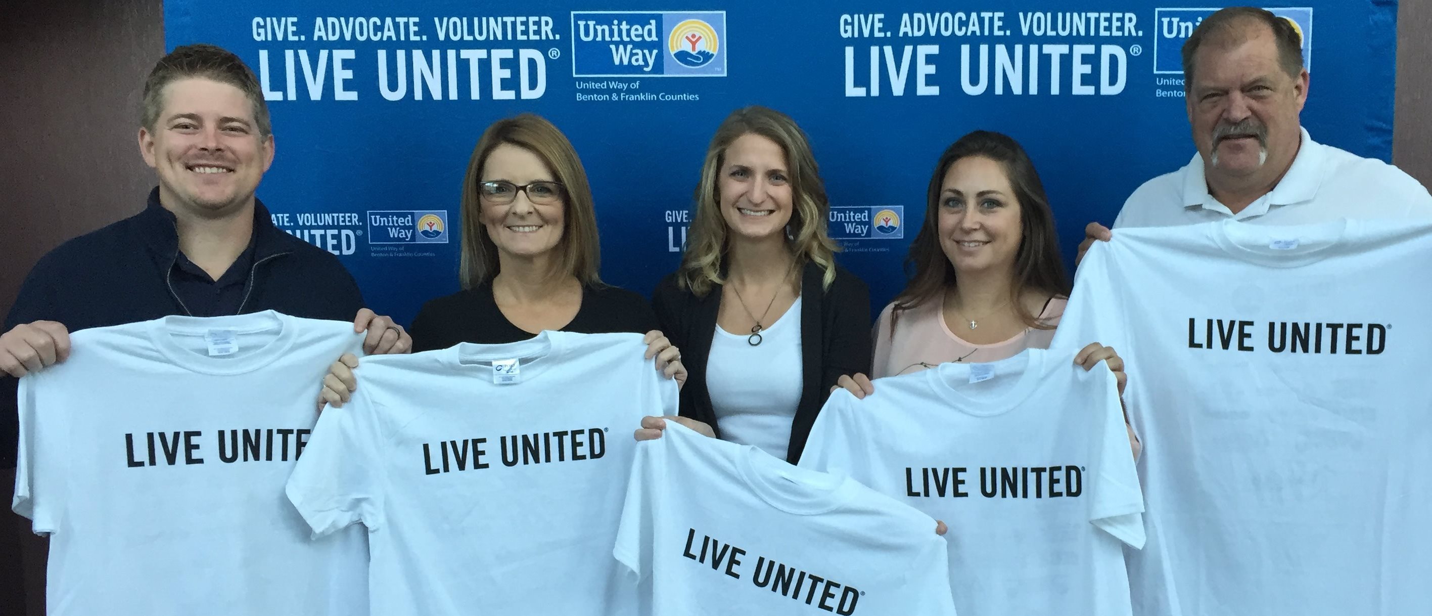 Benton PUD employees holding United Way shirts at community event.